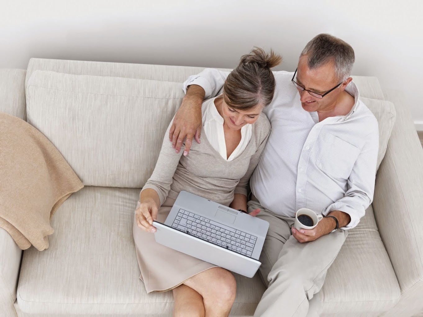Man and woman sitting on love seat looking at laptop in woman's lap