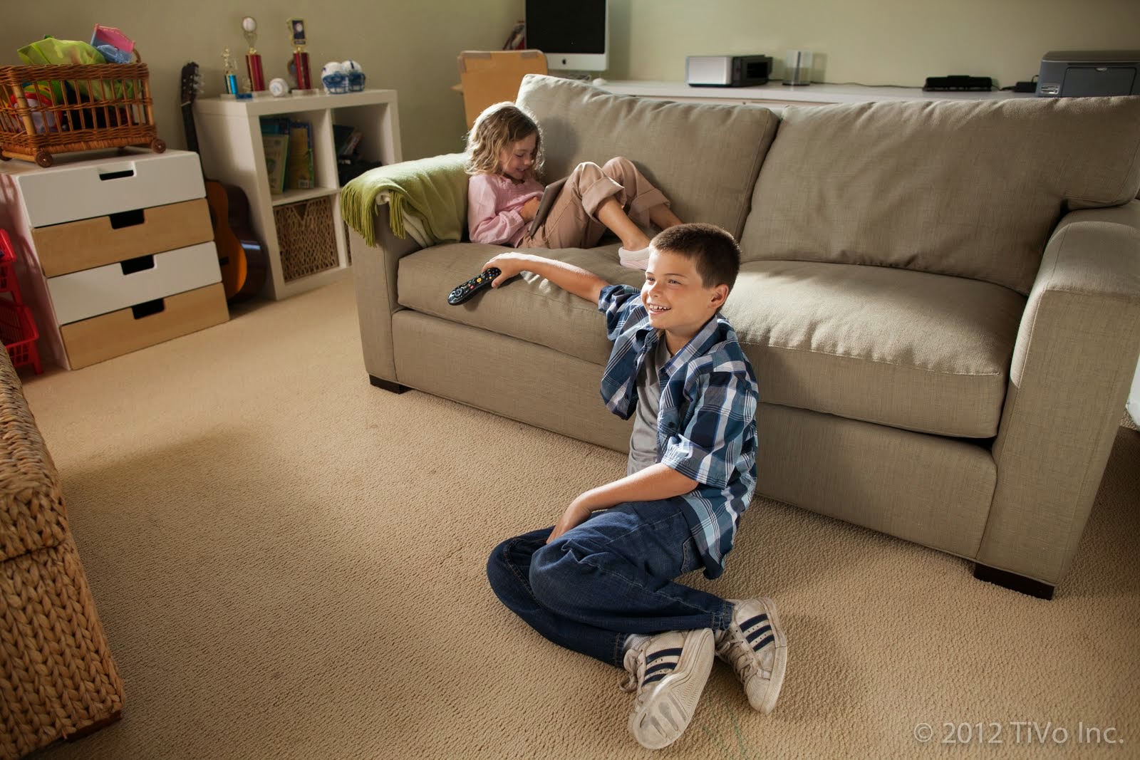 Boy watching tv while girl looks at tablet in the Livingroom